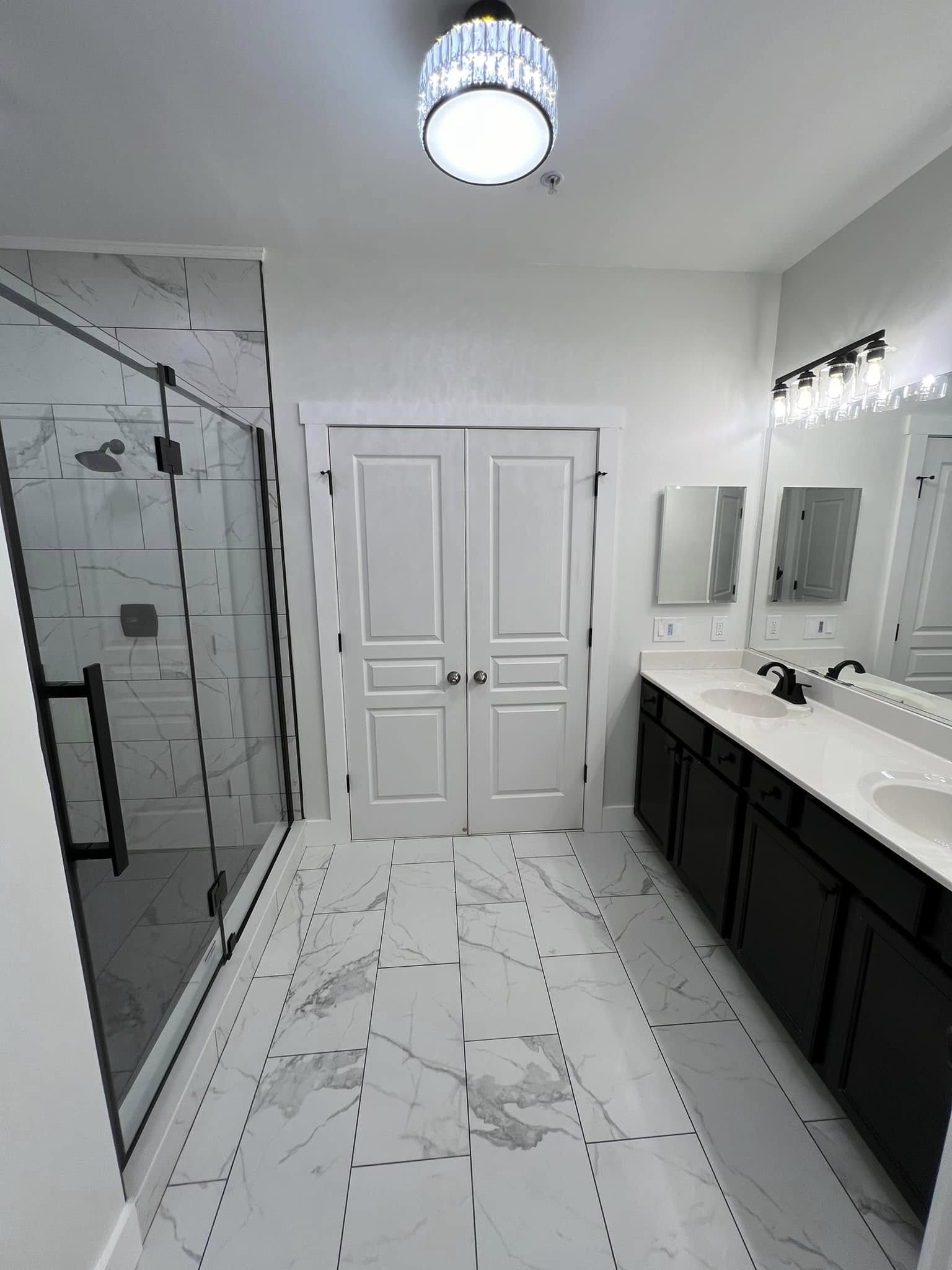 Walk-in glass shower and marble-look tile in a remodeled bathroom