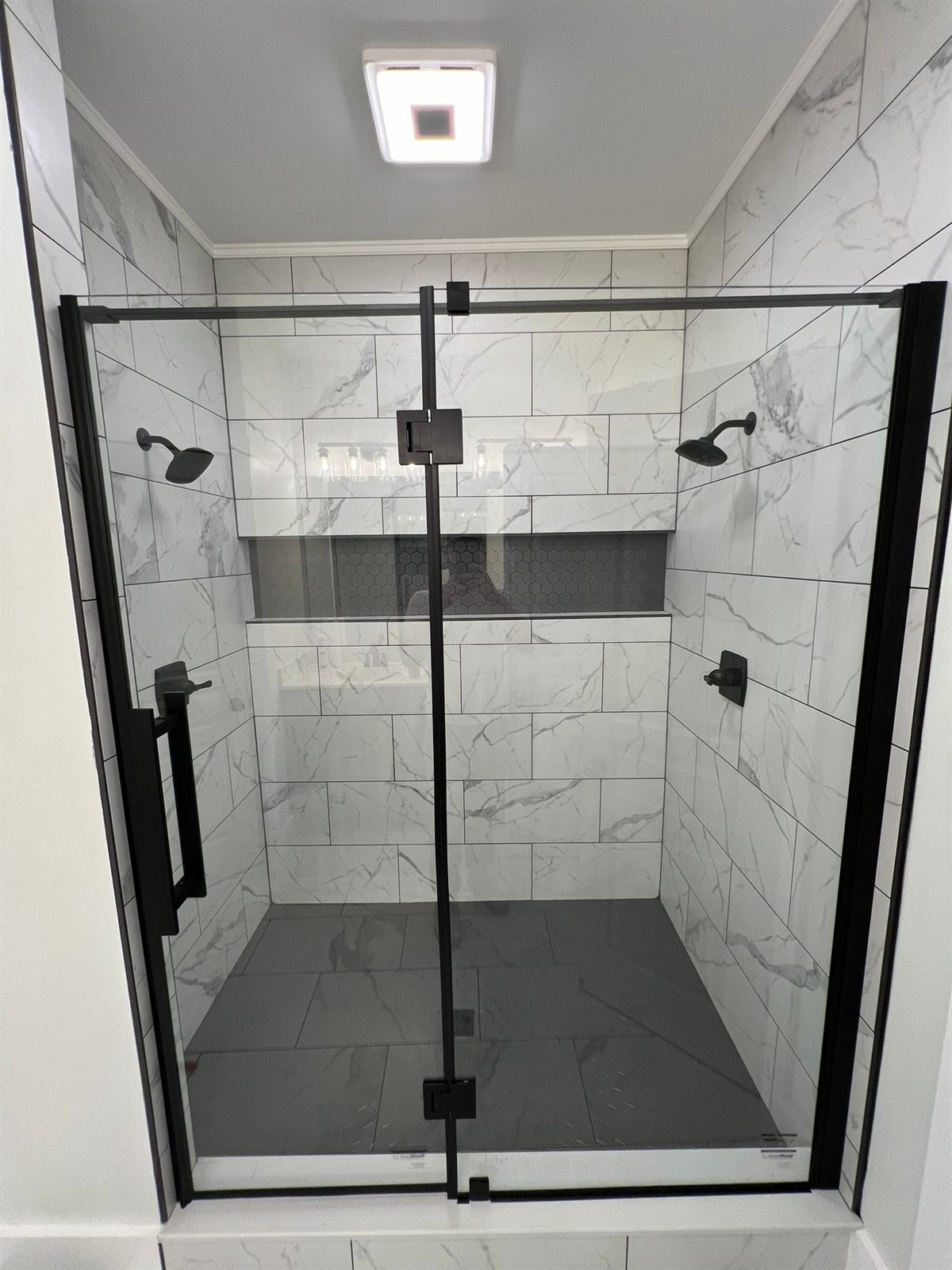 Walk-in marble-tile shower with dual shower heads and matte black fixtures