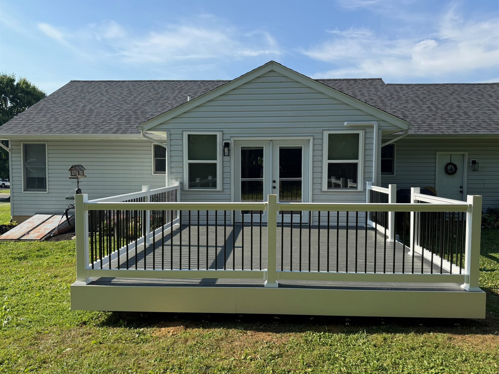 Composite deck with white railings and black balusters on a sunny day