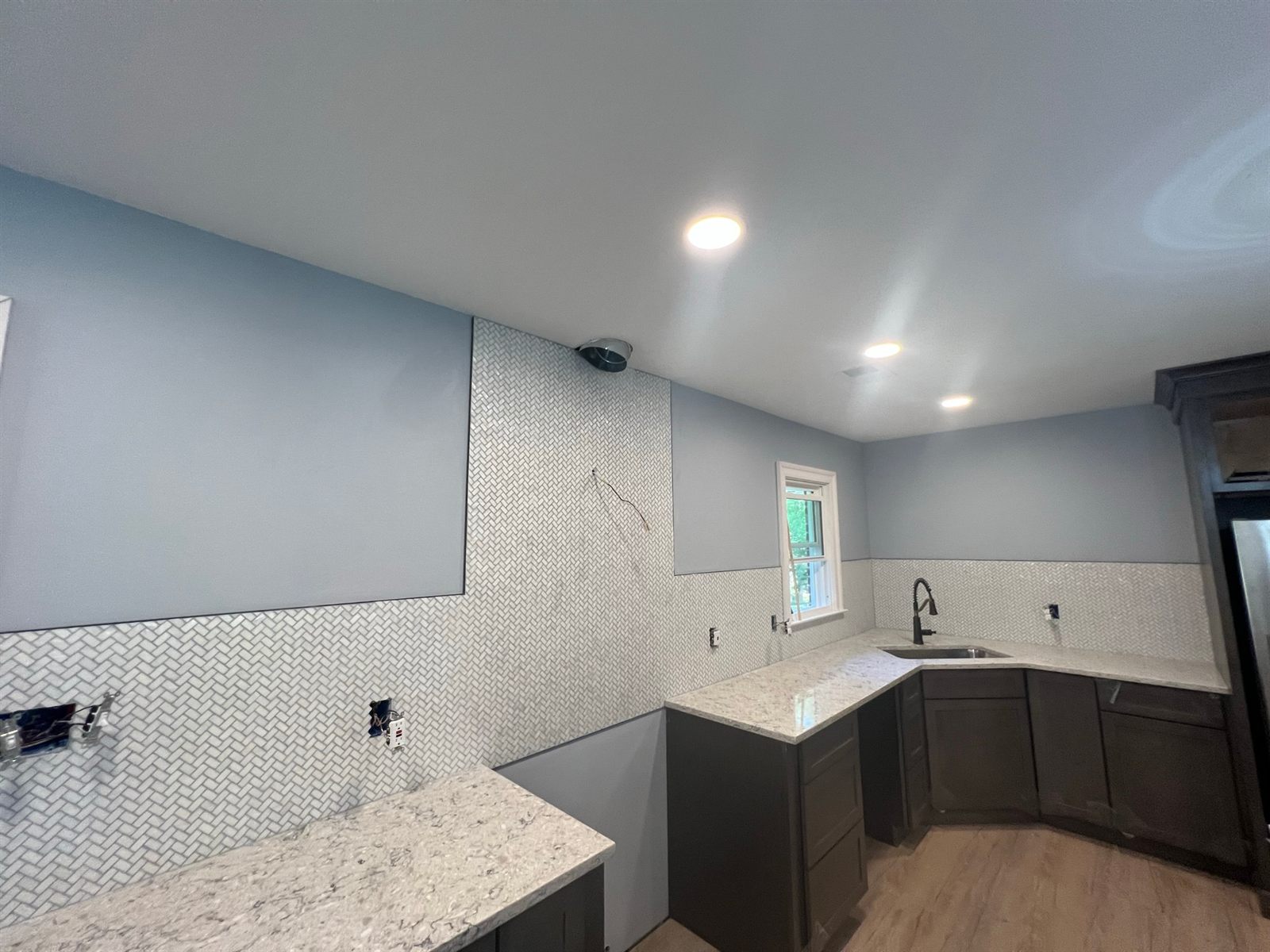 Kitchen remodel with herringbone marble backsplash, quartz counters, and dark cabinets
