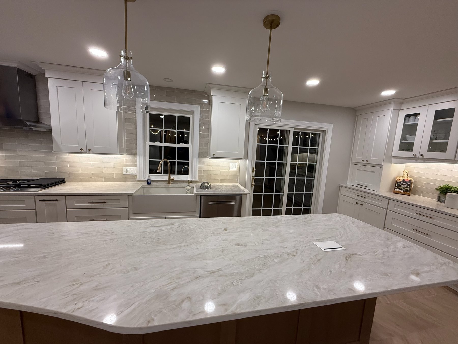 Completed Phoenix kitchen with a long island, white cabinetry, apron-front sink, and pendant lights