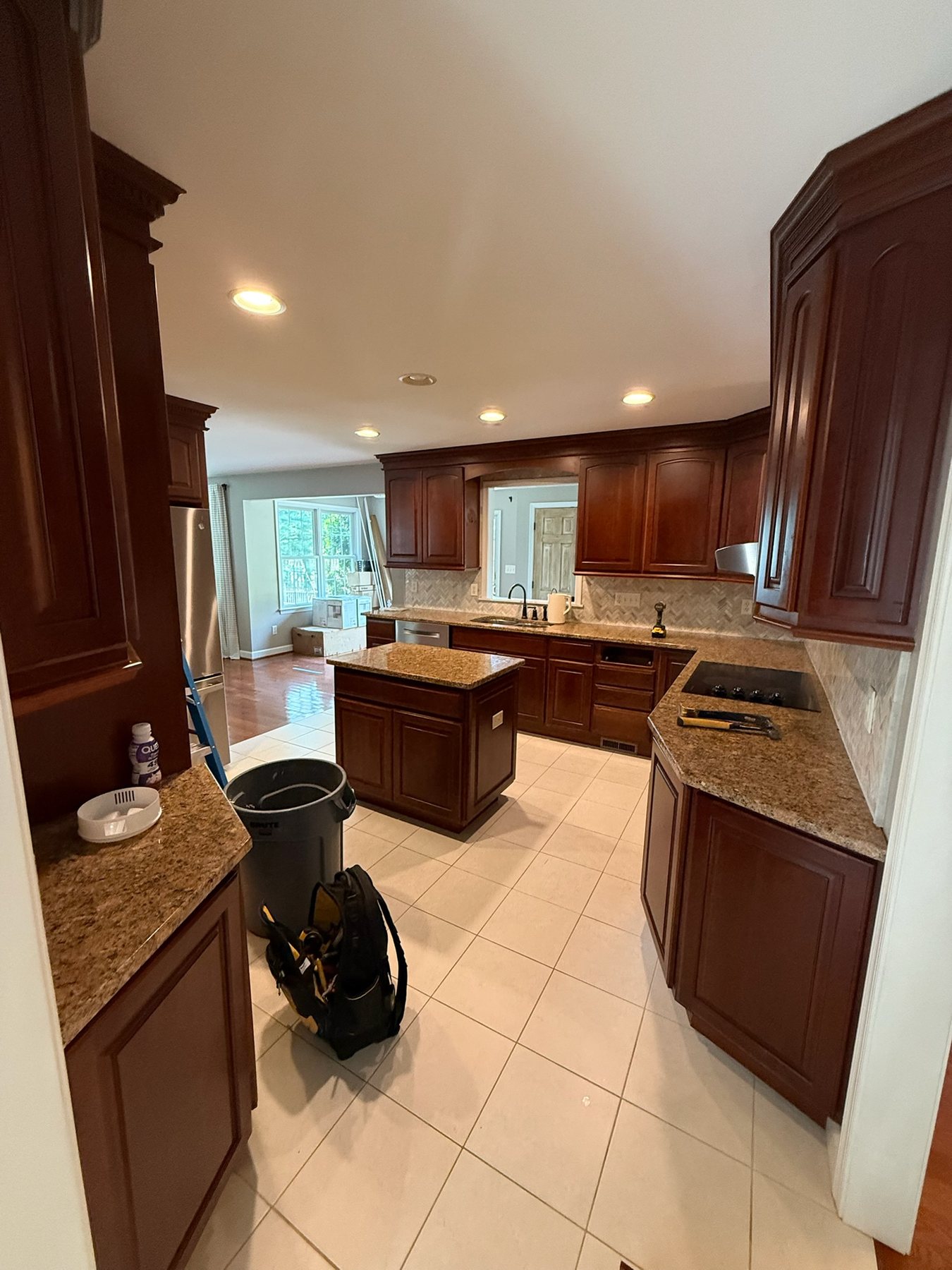 Before the remodel: dark wood cabinets, a compact island, and a light tile floor